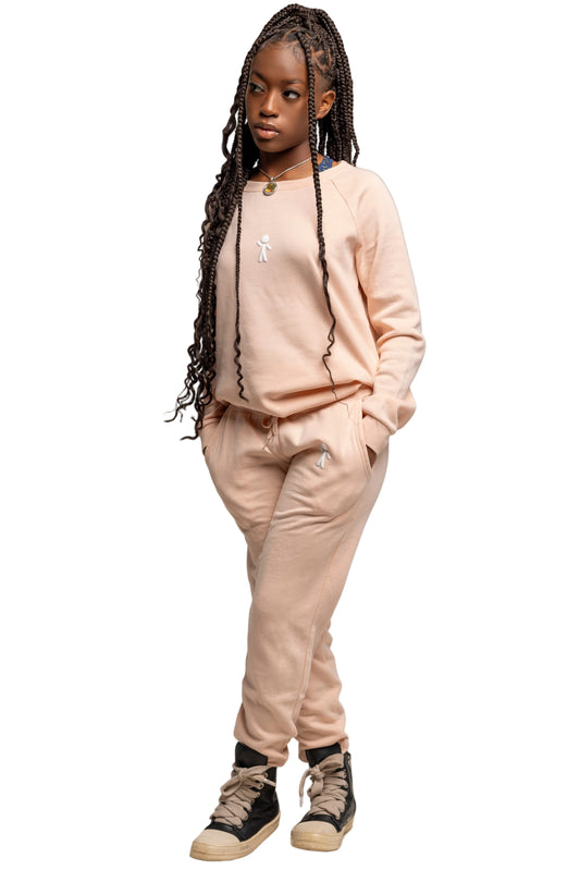 A young lady wearing a blush pink outfit with a plain background